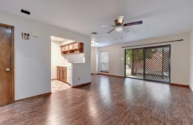 a view of a room with wooden floor ceiling fan and windows