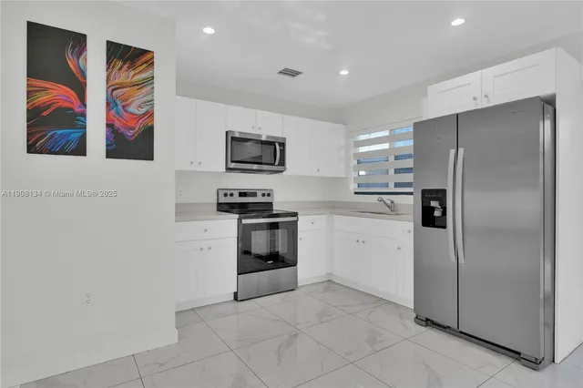 a kitchen with stainless steel appliances granite countertop a refrigerator a stove a sink and a microwave