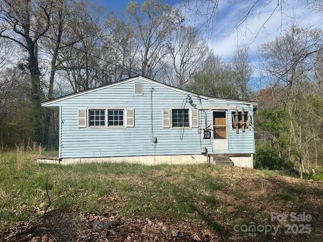 a backyard of a house with large trees and wooden fence