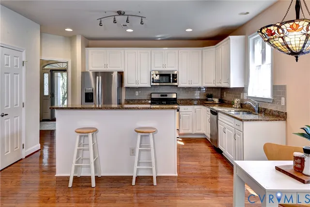 a kitchen with stainless steel appliances granite countertop a refrigerator a stove a sink and a microwave