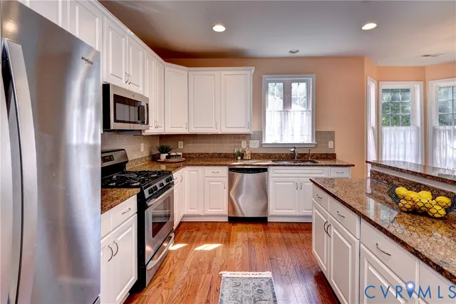 a kitchen with stainless steel appliances granite countertop a sink refrigerator and microwave