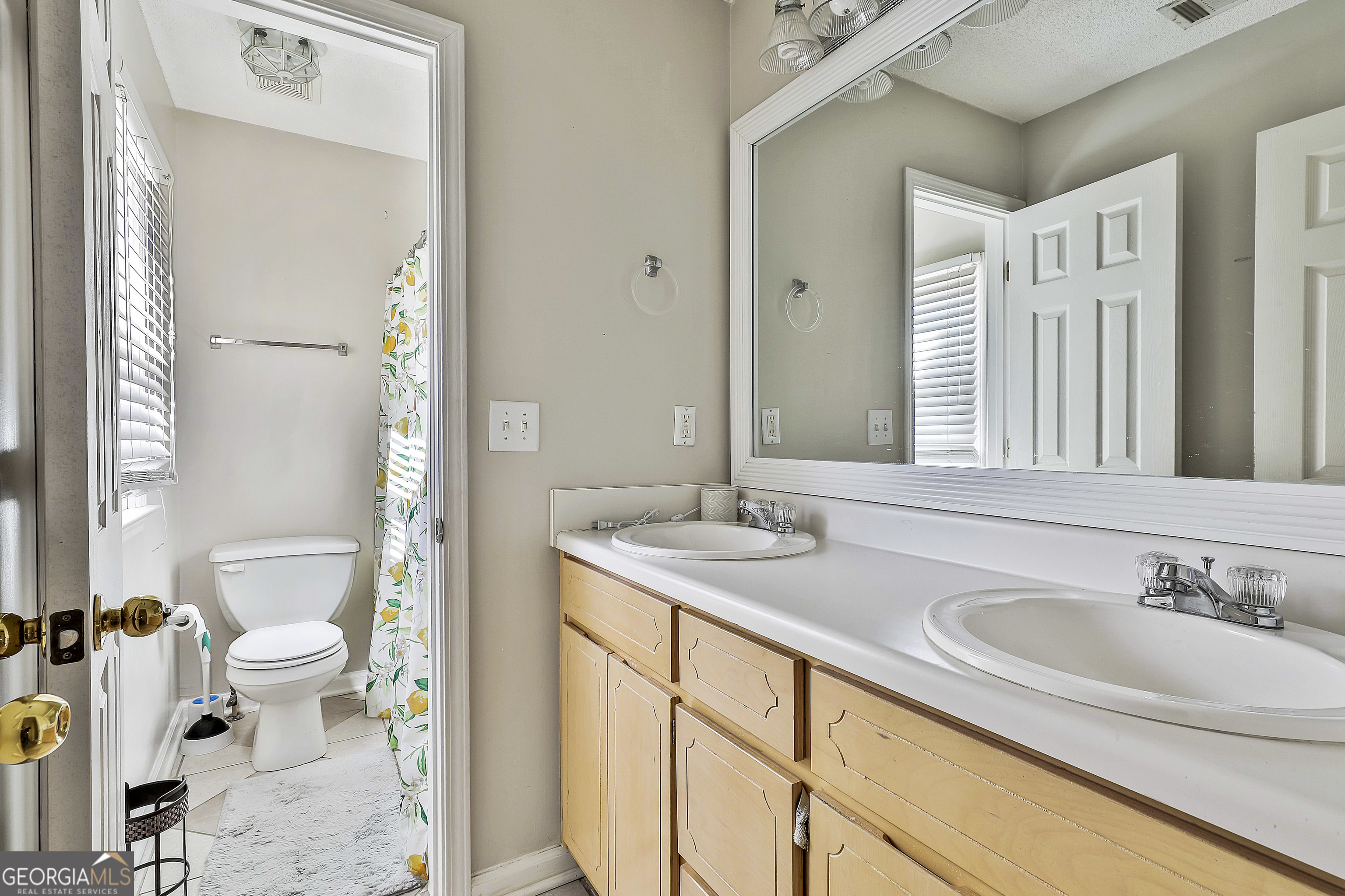 1317 Cheatham Road Griffin, GA 30223 - Photo 34 of 41 a bathroom with a granite countertop sink mirror and a toilet