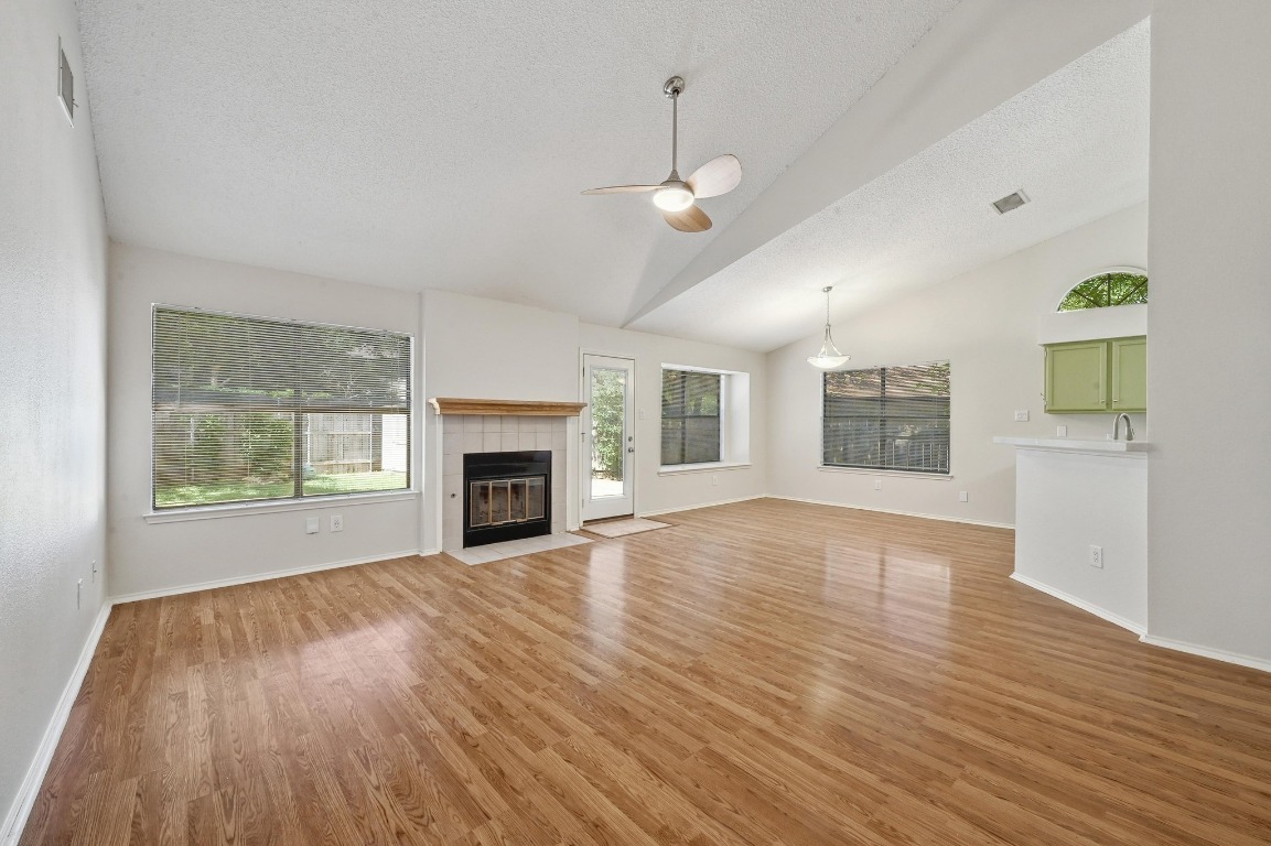 7201 Pine Bluffs Trail Austin, TX 78729 - Photo 3 of 25 an empty room with windows fireplace and wooden floor