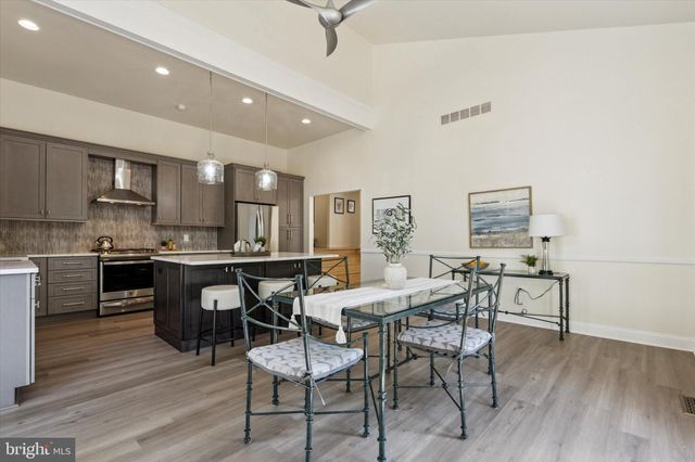 a kitchen with stainless steel appliances kitchen island granite countertop a refrigerator a stove a sink a dining table and chairs with wooden floor