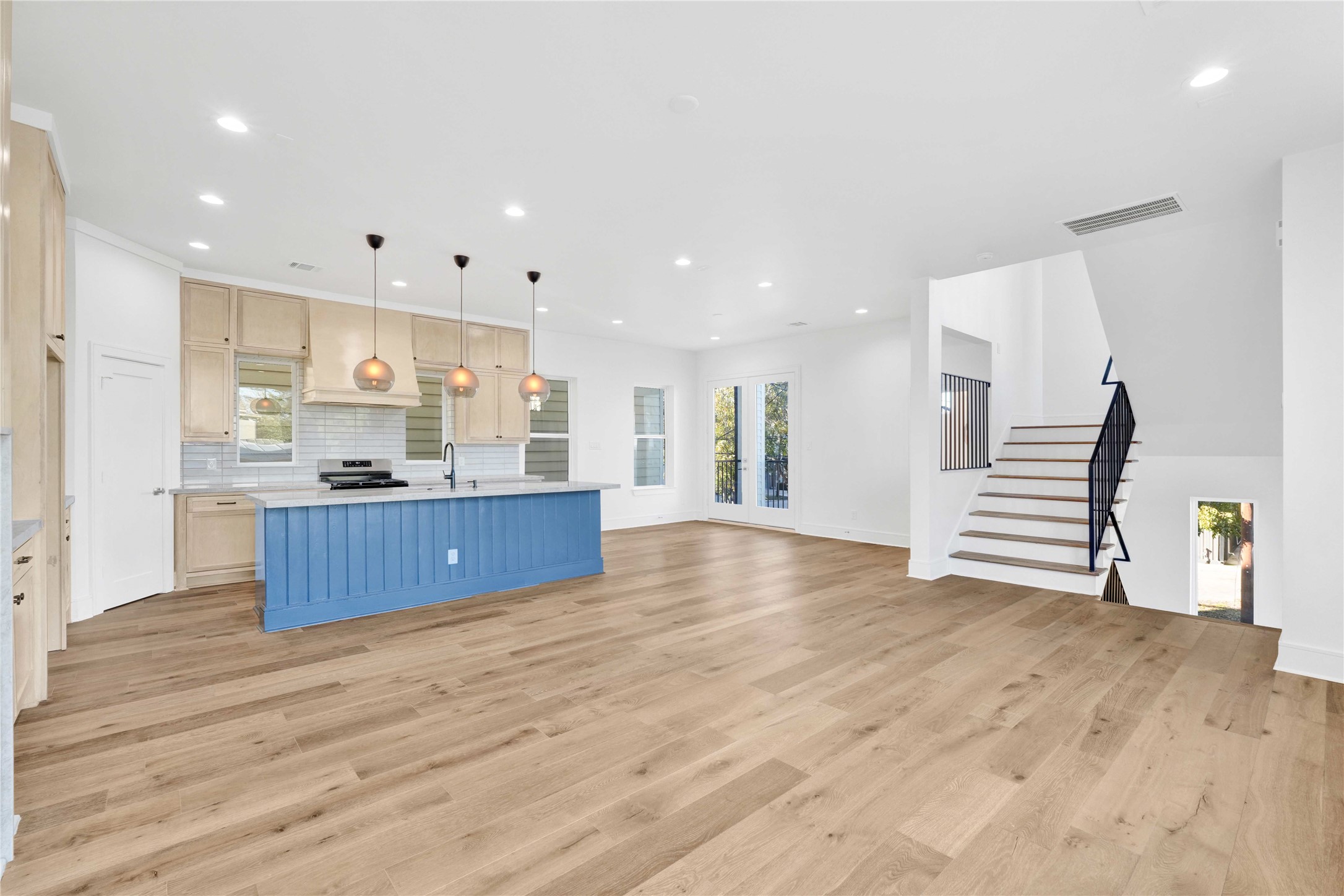 5439 Darling Street Houston, TX 77007 - Photo 12 of 42 Second-floor main living and kitchen area with abundant natural light, high ceilings, engineered wood floors, custom built-ins, and a stunning custom fireplace as the focal point. Features an oversized island with Taj Mahal quartzite countertops and integrated appliances.