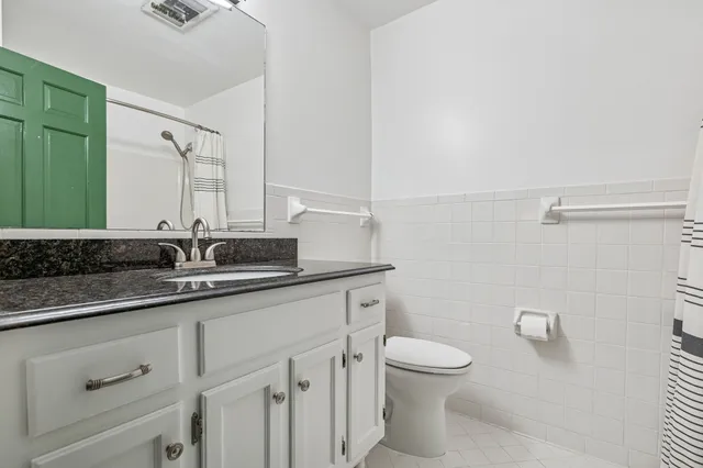 a bathroom with a granite countertop sink a toilet and a mirror