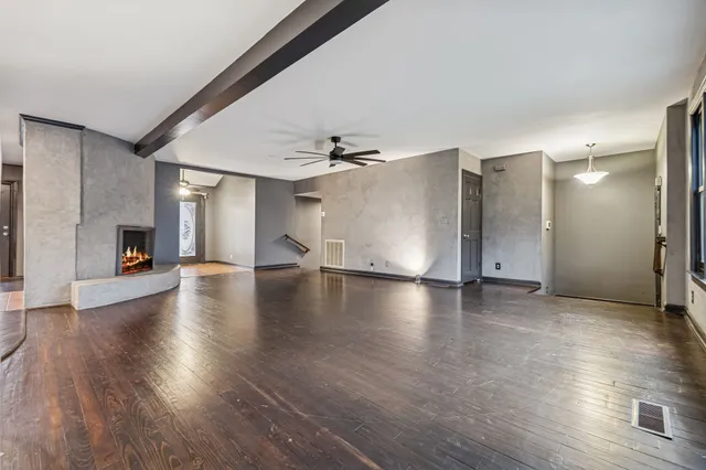 a view of a livingroom with wooden floor a ceiling fan and a kitchen