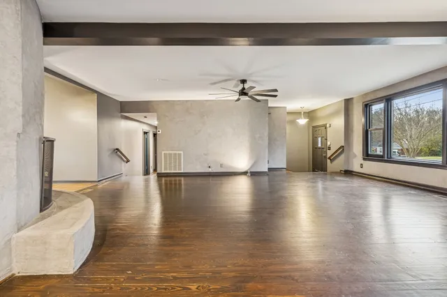 a view of a livingroom with wooden floor a ceiling fan and windows