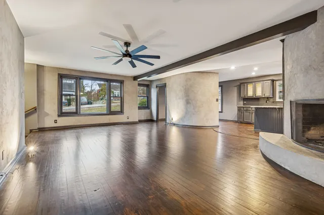 an empty room with wooden floor fireplace and a window