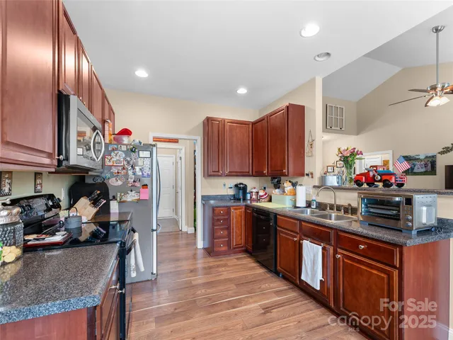 a kitchen with stainless steel appliances granite countertop a refrigerator a stove top oven a sink and dishwasher