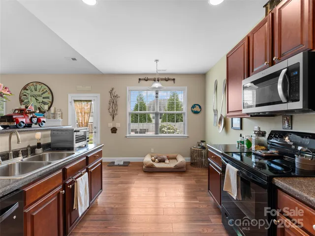 a kitchen with stainless steel appliances granite countertop a stove a sink and a microwave