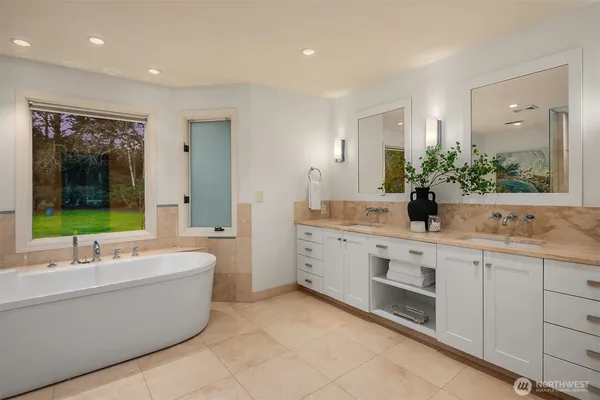 a large white bathroom with a large tub sink and mirror