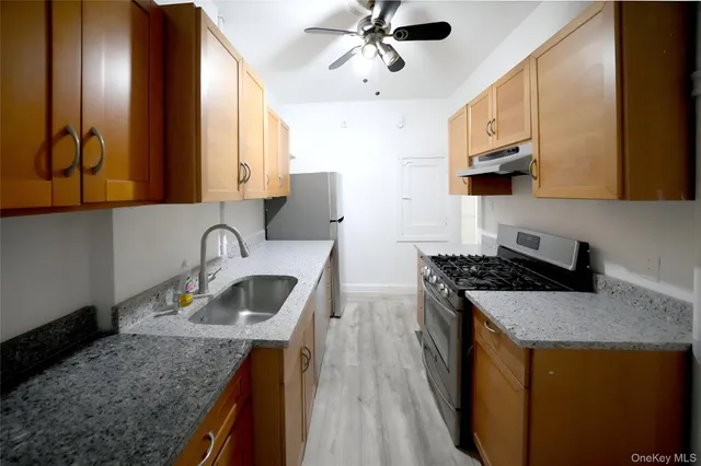 a kitchen with granite countertop a sink a stove and a wooden cabinets