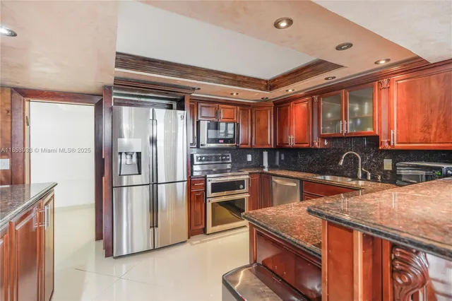 a kitchen with stainless steel appliances granite countertop a refrigerator a sink dishwasher a stove and white countertops with wooden floor