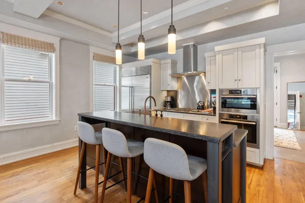 a kitchen with granite countertop a table chairs stove and wooden floor