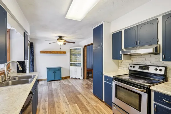 a kitchen with granite countertop a sink cabinets and stainless steel appliances