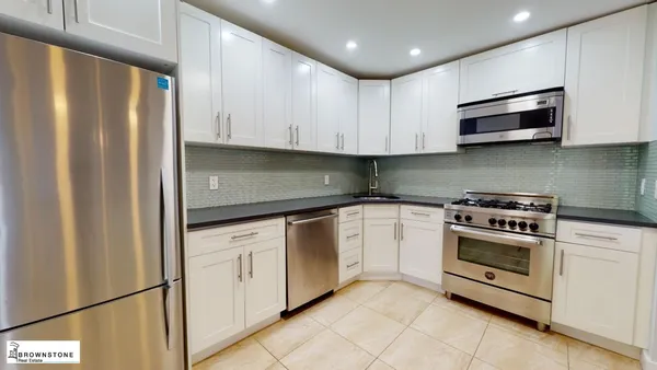 a kitchen with stainless steel appliances granite countertop a refrigerator and a stove top oven