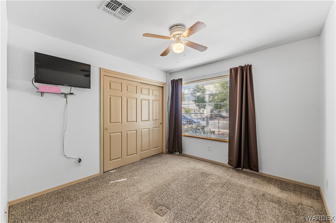 3973 Prairie View Drive Kingman, AZ 86409 - Photo 23 of 34 This room features neutral-toned walls, a window with a view of greenery, and a ceiling fan with integrated lighting