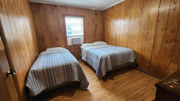 a bedroom with two beds and wooden floor