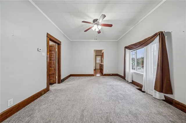 an empty room with chandelier fan and windows