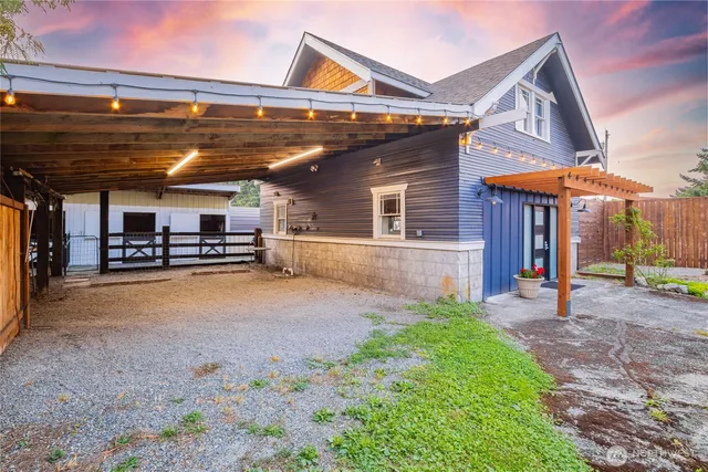 a view of a backyard with table and chairs potted plants and large tree