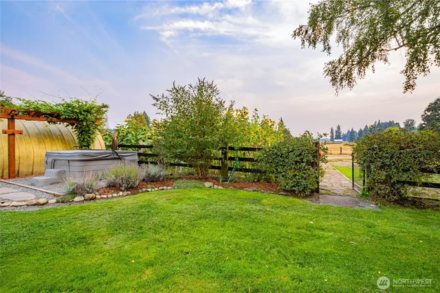 a view of a backyard with table and chairs potted plants and large tree