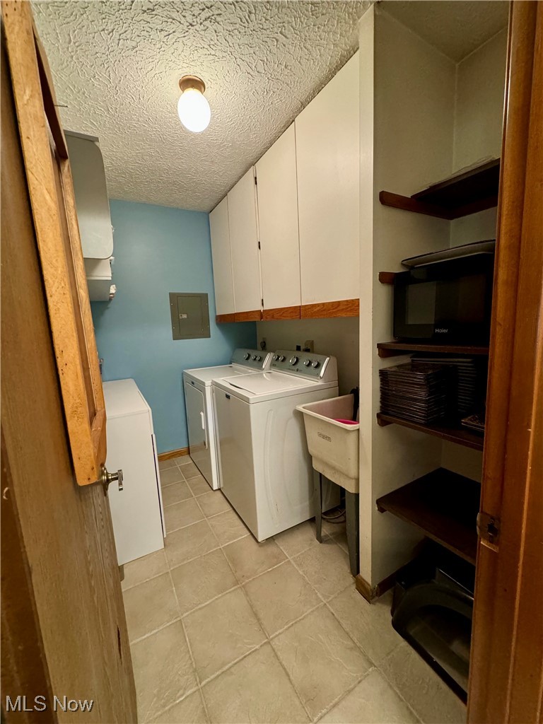 1499 Welch Road Painesville, OH 44077 - Photo 15 of 22 Clothes washing area with sink, washing machine and clothes dryer, light tile patterned flooring, cabinets, and a textured ceiling
