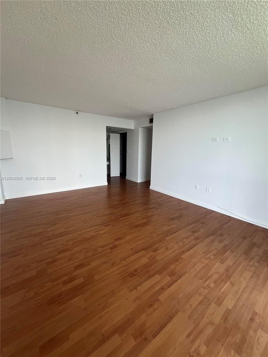 17500 North Bay Road, Unit S907 Sunny Isles Beach, FL 33160 - Photo 19 of 24 a view of an empty room with wooden floor and a window