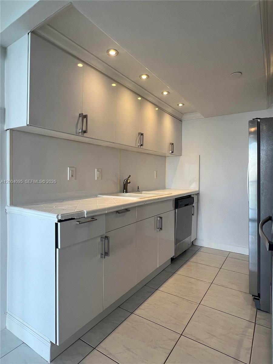 17500 North Bay Road, Unit S907 Sunny Isles Beach, FL 33160 - Photo 6 of 24 a kitchen with a sink stainless steel appliances and cabinets
