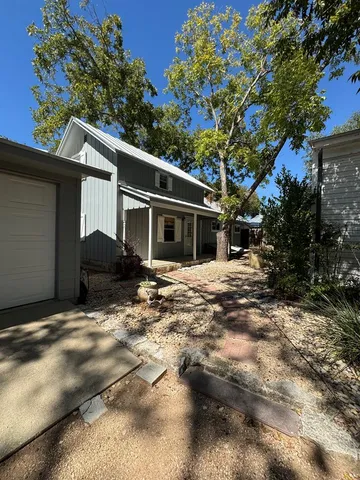 a backyard of a house with large trees and table and chairs