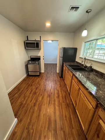 a kitchen with stainless steel appliances granite countertop a stove a sink and a microwave