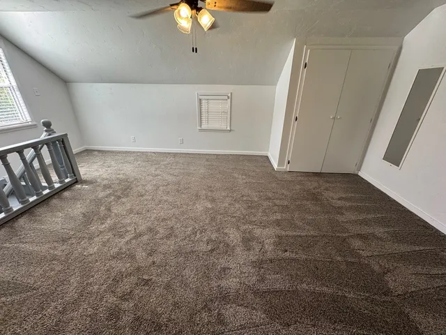 an empty room with chandelier fan and windows