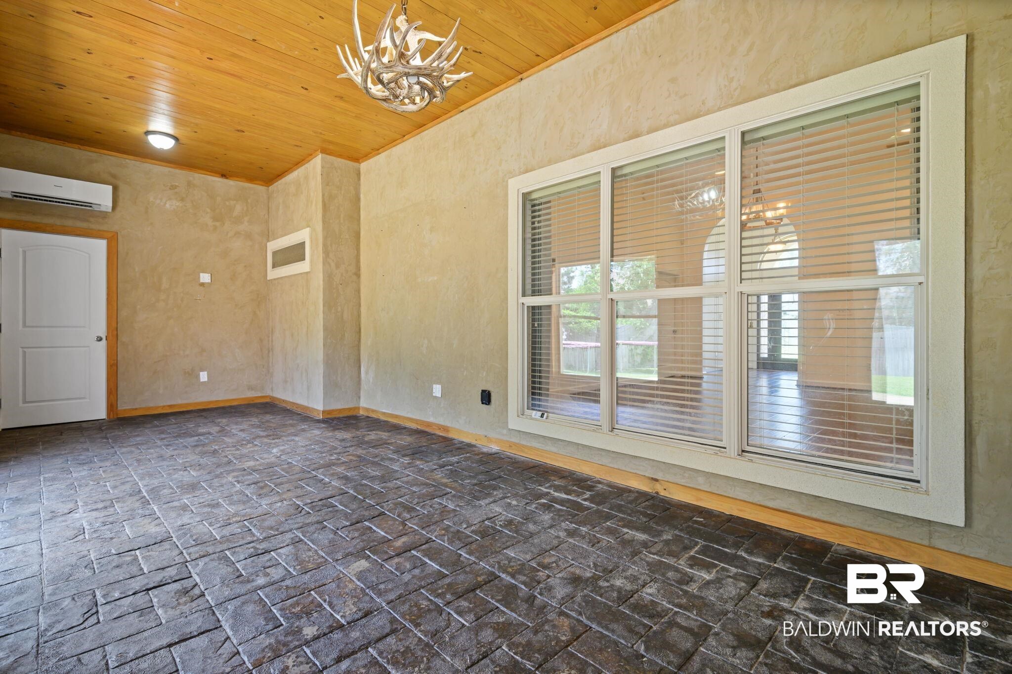 9730 Harmony Ridge Circle West Semmes, AL 36575 - Photo 31 of 38 Unfurnished room featuring a wall mounted air conditioner, a chandelier, wood ceiling, baseboards, and brick flooring