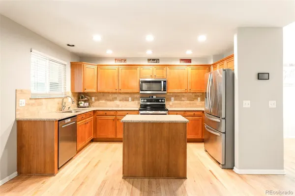 a kitchen with stainless steel appliances granite countertop a refrigerator a sink dishwasher a stove and white countertops with wooden floor