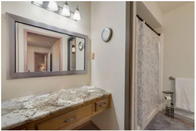 a bathroom with a granite countertop sink a mirror and shower