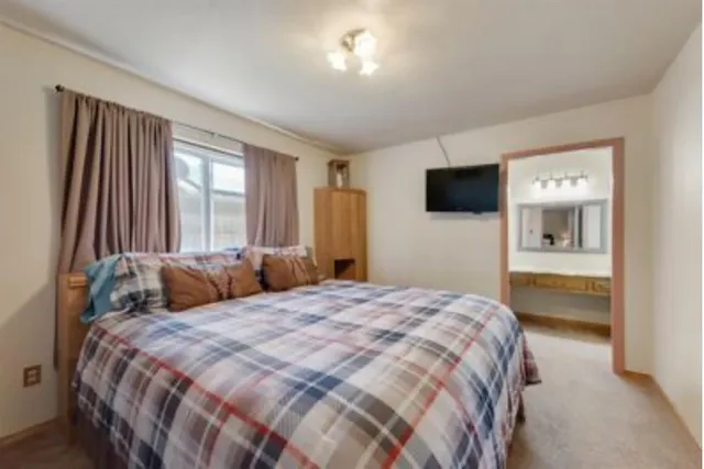 a bedroom with a bed and a flat tv screen on dresser