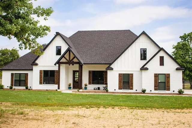 a view of a yard in front of a house with plants and large tree