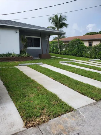 a front view of a house with a yard and potted plants