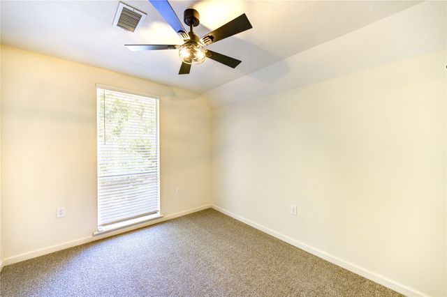 an empty room with a window and a ceiling fan