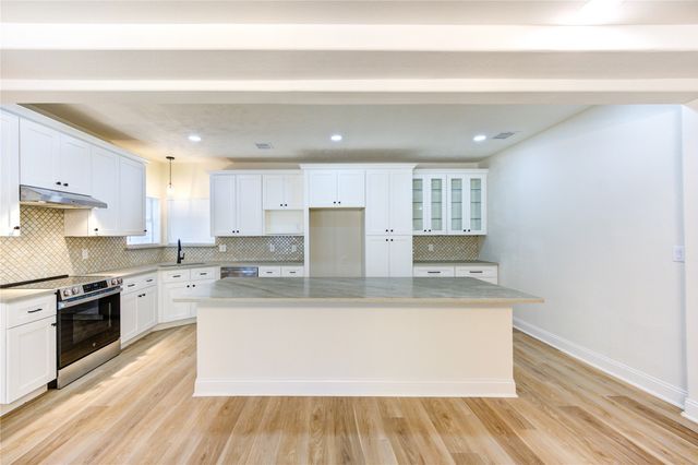 a large kitchen with stainless steel appliances granite countertop a stove a sink and a refrigerator