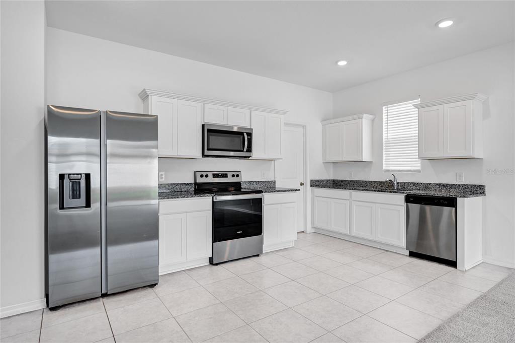 5875 Herder Road St. Cloud, FL 34771 - Photo 7 of 42 a kitchen with stainless steel appliances granite countertop a refrigerator and a stove top oven