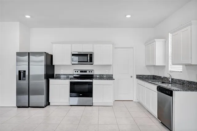 a kitchen with stainless steel appliances granite countertop a refrigerator a sink a stove a microwave and island