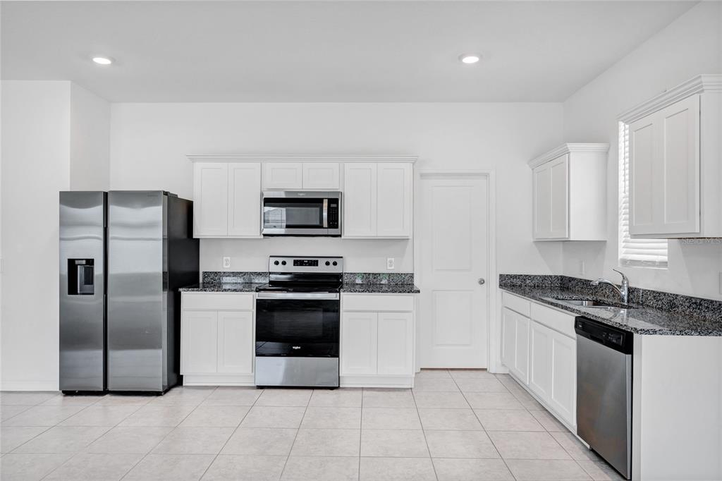 5875 Herder Road St. Cloud, FL 34771 - Photo 8 of 42 a kitchen with stainless steel appliances granite countertop a refrigerator a sink a stove a microwave and island
