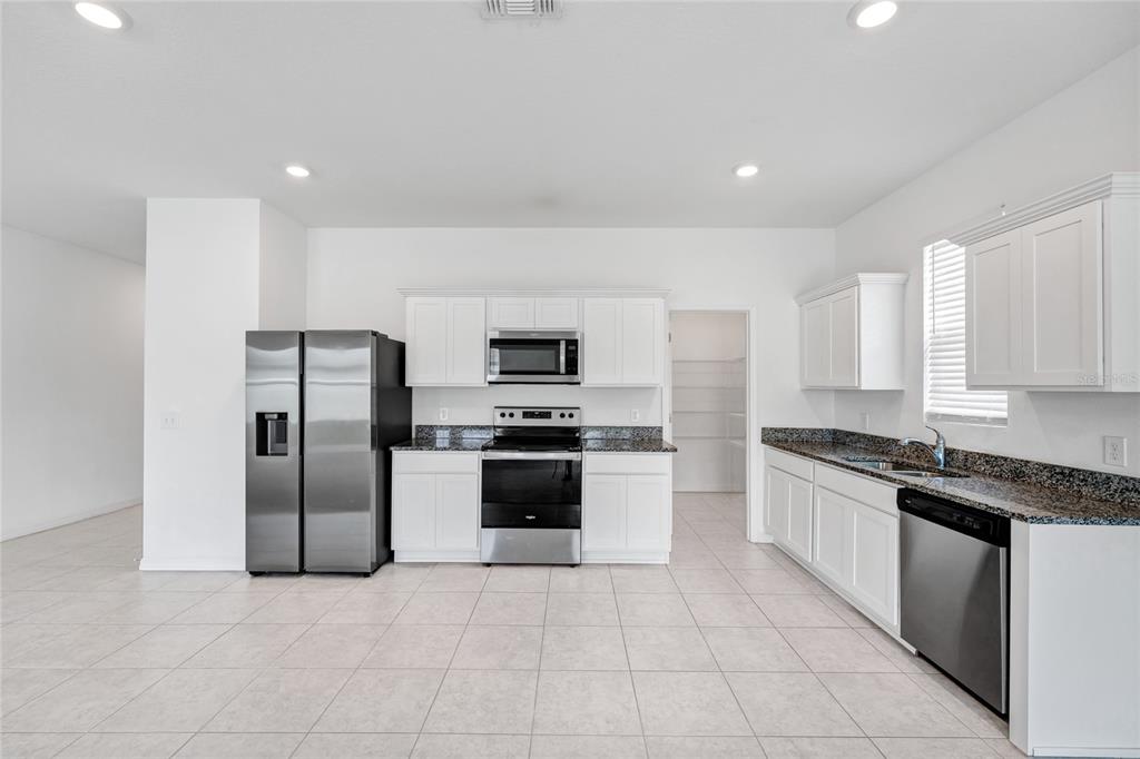 5875 Herder Road St. Cloud, FL 34771 - Photo 9 of 42 a large kitchen with stainless steel appliances granite countertop a stove a sink and a refrigerator