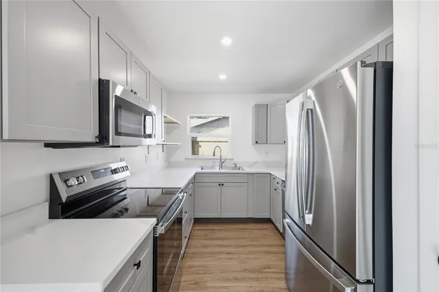 a kitchen with stainless steel appliances a refrigerator sink and microwave