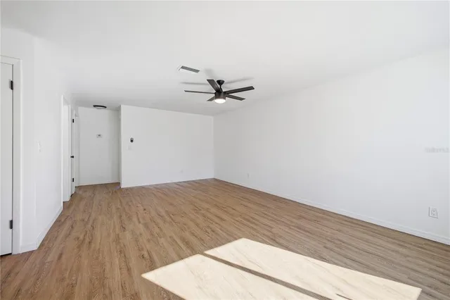 an empty room with a ceiling fan and wooden floor