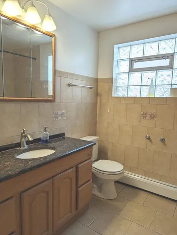 a bathroom with a granite countertop sink a toilet and a mirror