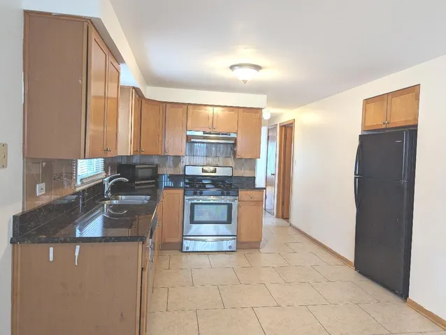 a kitchen with granite countertop a refrigerator and a stove top oven