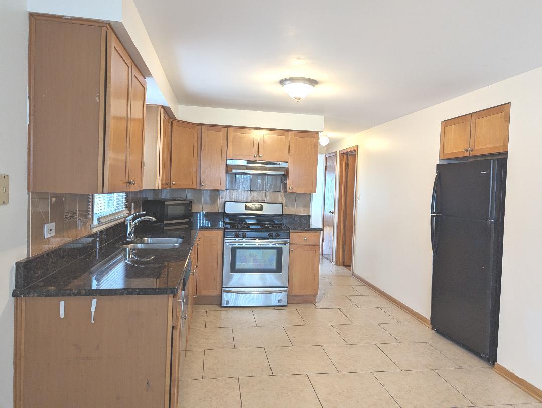 6134 West 79th Street, Unit 1 Burbank, IL 60459 - Photo 5 of 19 a kitchen with granite countertop a refrigerator and a stove top oven