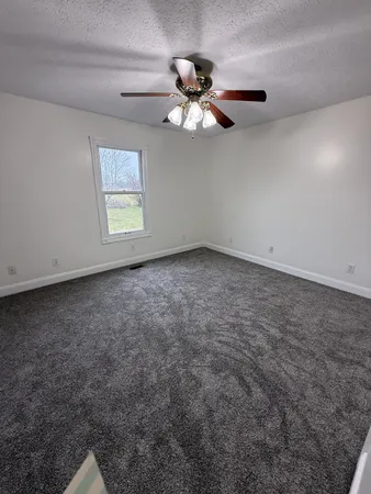 an empty room with windows and fan